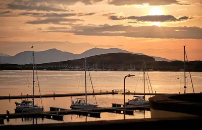 a group of boats docked at a marina at sunset at Muthu Oban Regent Hotel in Oban