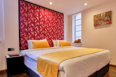 a bedroom with a large bed with a red wall at Muthu Oban Regent Hotel in Oban