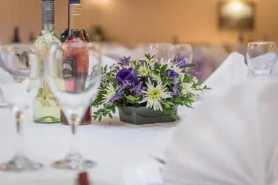 a table with wine glasses and a vase of flowers at The Royal Hotel in Oban