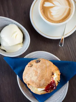 a muffin on a plate next to a cup of coffee at The Perle Oban Hotel & Spa in Oban