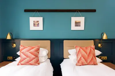 two beds in a room with a blue wall at The Perle Oban Hotel & Spa in Oban