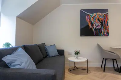 a living room with a couch and a painting of a tiger at Combie Lane Apartment in Oban