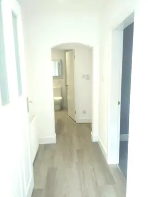 an empty hallway with white walls and wood floors at J & S Apartments in Ayr