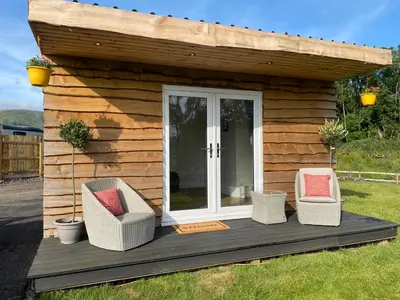 a tiny house with two chairs and a porch at Devon River Glamping Pods in Alloa