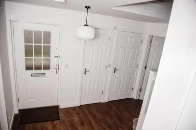 a hallway with white doors and wood floors at Beautiful 5 Bedroom House in Glasgow in Cambuslang