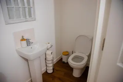 a white bathroom with a toilet and a sink at Beautiful 5 Bedroom House in Glasgow in Cambuslang