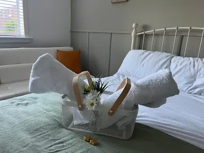 a basket of towels and flowers on a bed at Erskine Apartment in Erskine