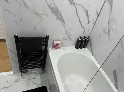 a bathroom with a white tub and a black chair at Erskine Apartment in Erskine