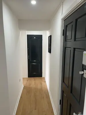a hallway with a black door and a wooden floor at Erskine Apartment in Erskine