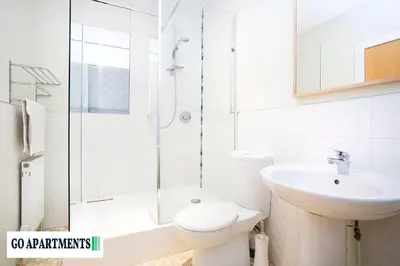 a white bathroom with a shower and a toilet and a sink at Large 2 Bed Edinburgh City Centre Apartment - FREE Parking in Edinburgh