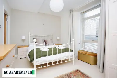 a white bedroom with a bed and a window at Large 2 Bed Edinburgh City Centre Apartment - FREE Parking in Edinburgh