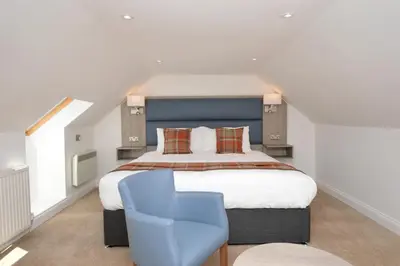 a bedroom with a large bed and a blue chair at Burnside in Tighnabruaich