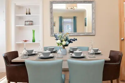 a dining room table with chairs and a mirror at Burnside in Tighnabruaich