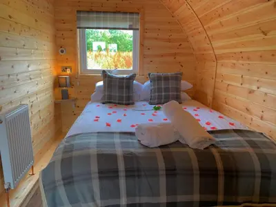 a bedroom with a bed in a wooden cabin at Pond View Pod 3 With Private Hot Tub -Fife - Loch Leven - Lomond Hills in Kelty