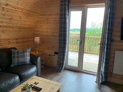 a living room with a couch and a balcony at Pond View Pod 3 With Private Hot Tub -Fife - Loch Leven - Lomond Hills in Kelty