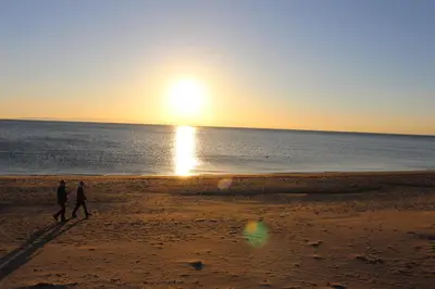two people walking on the beach at sunset at Horizon Hotel in Ayr