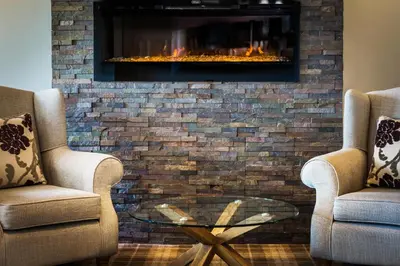 a living room with two chairs and a fireplace at Kinloch Hotel, Isle of Arran in Blackwaterfoot