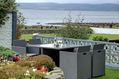 a patio with a table and chairs and the ocean at Kinloch Hotel, Isle of Arran in Blackwaterfoot