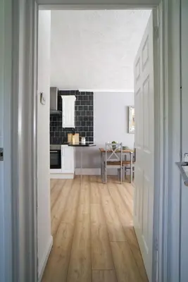 an open door into a kitchen with a wooden floor at Rotherwood Apartment in Glasgow