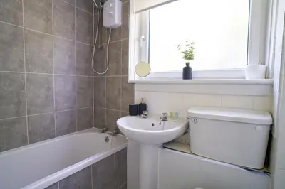 a bathroom with a sink and a toilet and a bath tub at Rotherwood Apartment in Glasgow