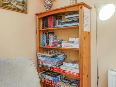 a book shelf filled with books next to a lamp at Bidean Lodge in Glencoe
