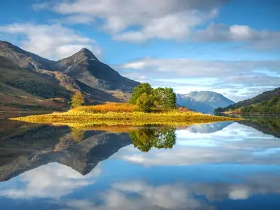 a lake with trees and mountains in the background at Bidean Lodge in Glencoe