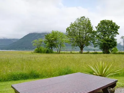 a picnic table in a field of grass with a mountain at Duart in Onich