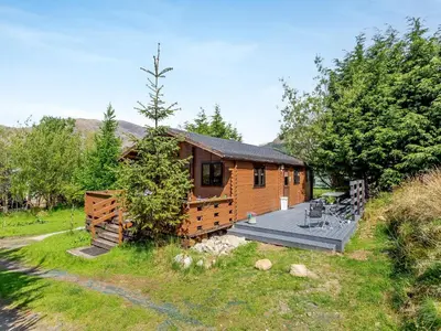 a log cabin with a deck in the yard at The Willows in Glencoe