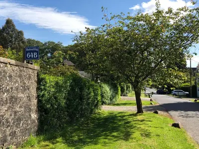 a speed limit sign on a wall next to a tree at Balmillig B&B in Helensburgh