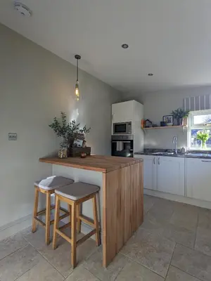 a kitchen with a wooden counter and stools in it at The Posting House in Kilchrenan