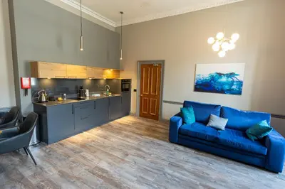 a living room with a blue couch and a kitchen at MONO Suites NEW TOWN in Edinburgh