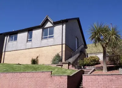 a house with a palm tree in front of it at Campbeltown View in Campbeltown