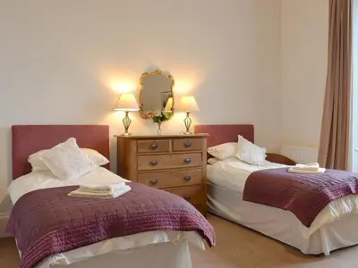 a bedroom with two beds and a dresser with a mirror at The Factors House - 25752 in Kilmartin