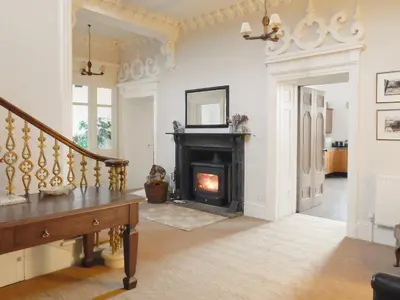 a living room with a fireplace and a staircase at The Factors House - 25752 in Kilmartin