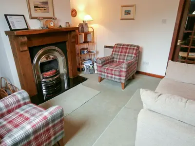 a living room with two chairs and a fireplace at 15 Cairnbaan Cottage in Cairnbaan