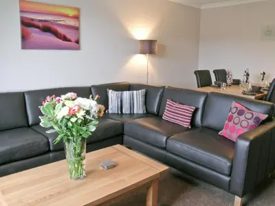 a living room with a couch and a vase of flowers on a table at Kerrera View in Oban