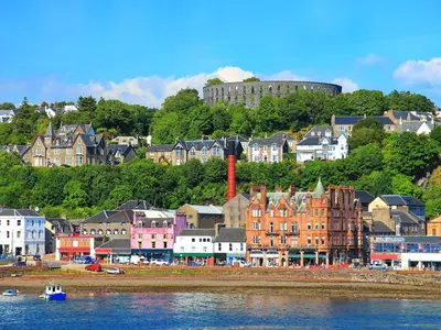 a group of buildings on a hill next to the water at Kerrera View in Oban