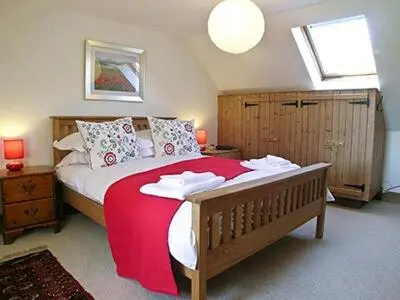 a bedroom with a large bed with a red blanket at Dalvuie Beag in Connel