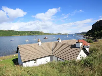 a house on the shore of a body of water with boats at Ardbhan Croft in Oban
