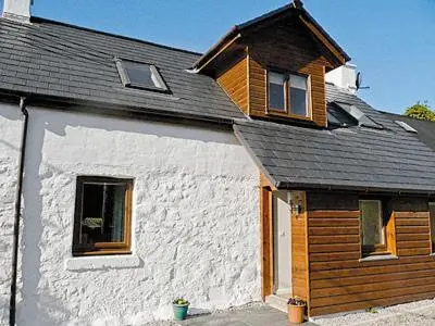 a white house with a gambrel roof and windows at Blackmill Cottage in Taynuilt