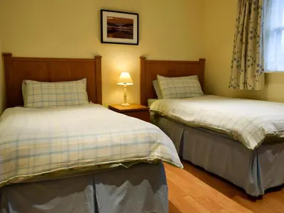 a bedroom with two beds and a lamp on a table at Inn Cottage in Glendevon