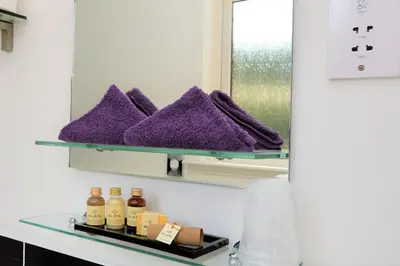 a bathroom mirror with purple towels on a shelf at Fyne Rooms in Tighnabruaich