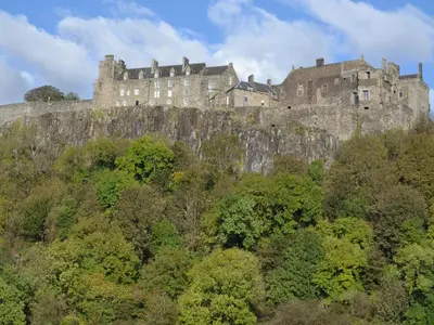 a castle on top of a hill with trees at Kestrel Cottage - 27937 in Stirling