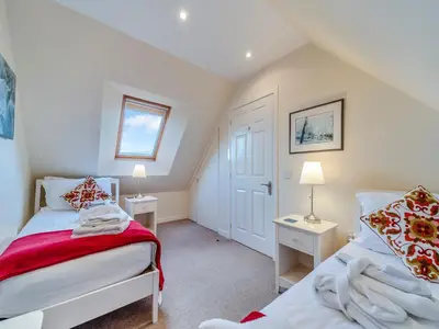 a bedroom with two beds and a window at Peregrine Cottage in Stirling
