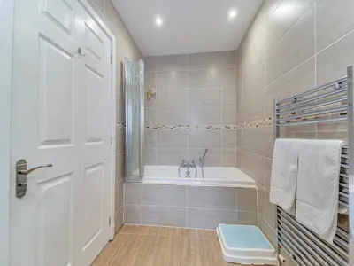 a white bathroom with a tub and a sink at Peregrine Cottage in Stirling