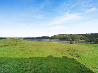 a green field with a lake in the distance at Peregrine Cottage in Stirling