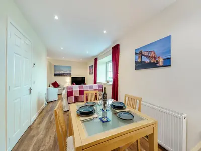 a dining room and living room with a table and chairs at Peregrine Cottage in Stirling
