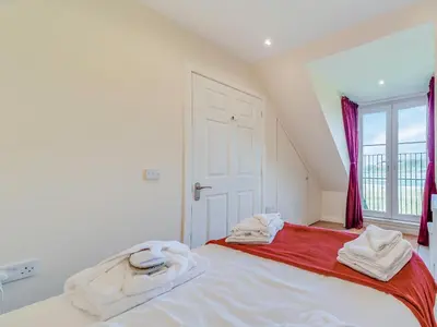 a bedroom with a large bed with towels on it at Peregrine Cottage in Stirling