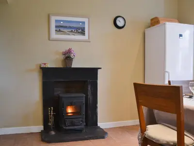 a living room with a fireplace and a refrigerator at Old Inzievar in Blairhall