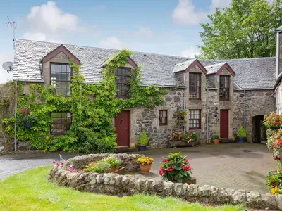 an old stone house with red doors and flowers at The Hayloft in Milnathort